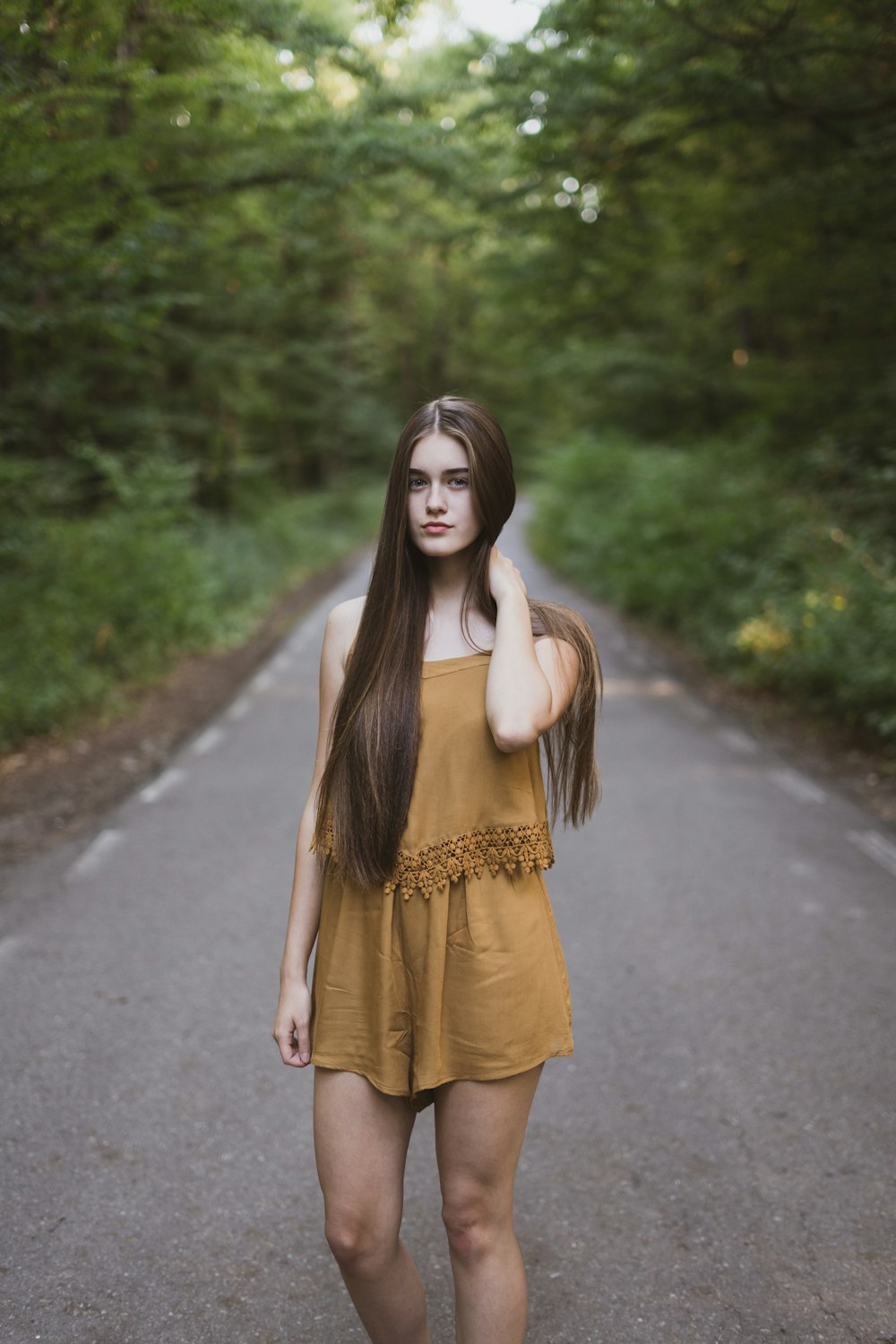 Woman with long hair in a yellow dress in the middle of a country road