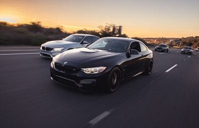 A convoy of cars driving safely on a highway at sunset.