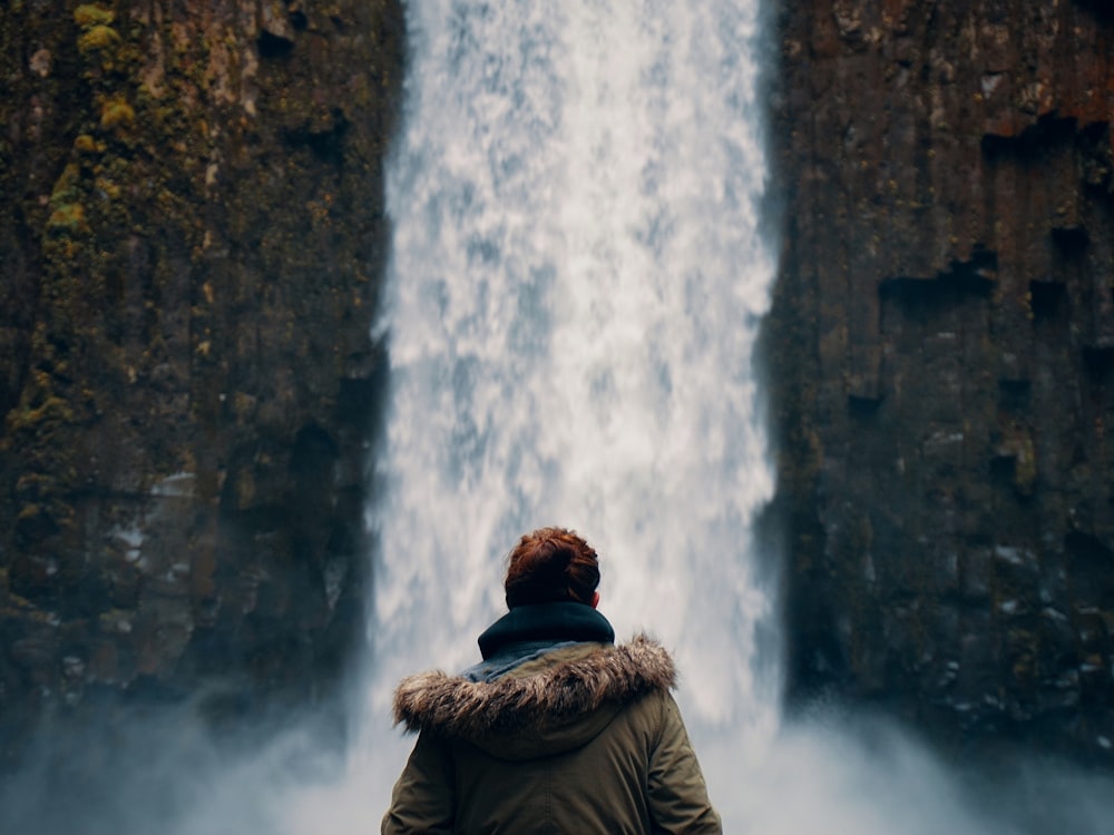 Mann steht vor Wasserfall