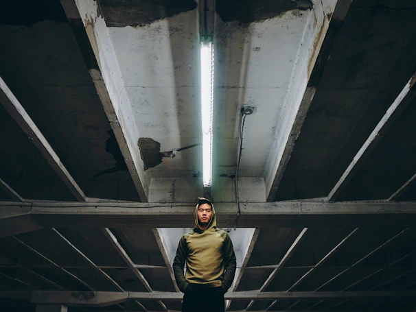 Close-up of a black hoodie with neon green stitching under moody industrial lighting.