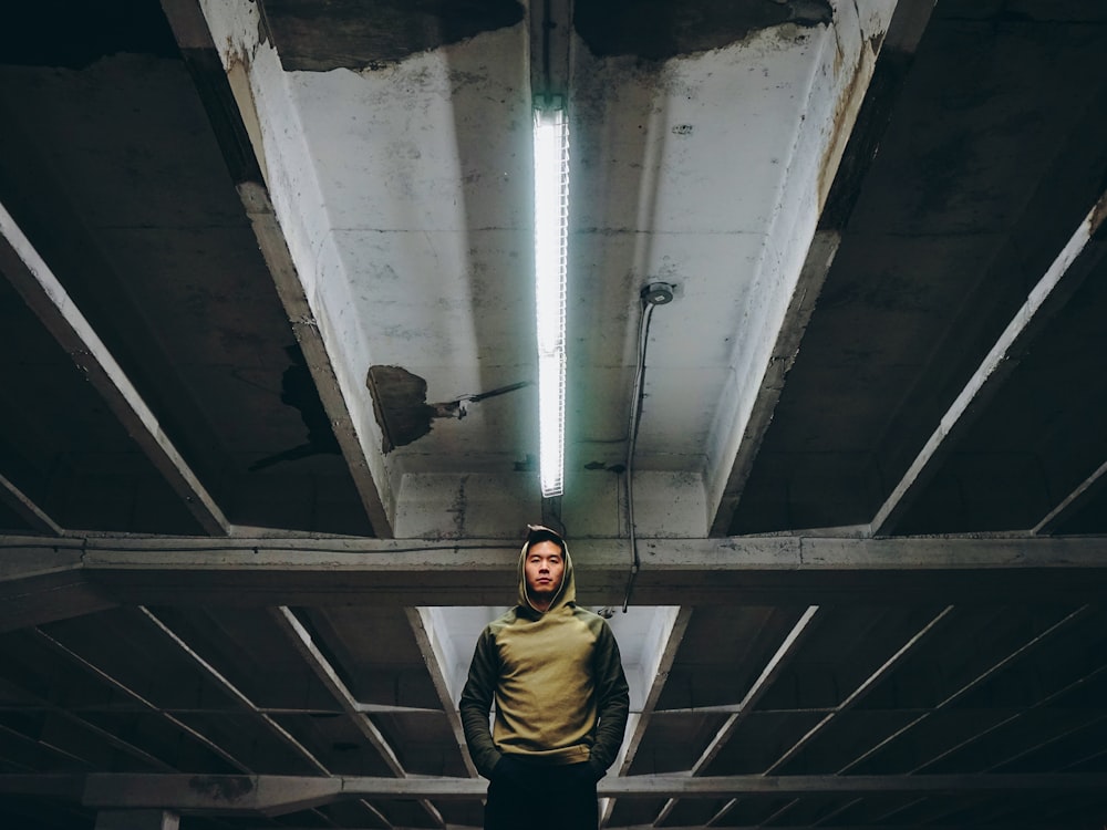 low-angle photography of man wearing hooding standing on underground parking lot