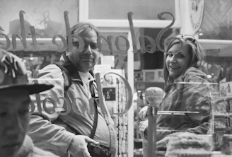 Photo of two smiling partners holding squeegees in front of a sparkling clean window.