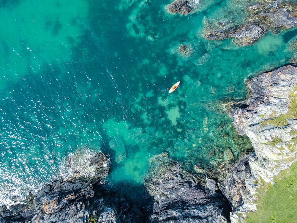 aerial view of boat on sea beside rock formation at daytime