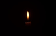 Close-up of a candle flame flickering softly against a dark background symbolizing guidance.