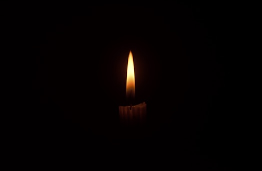A gentle candle flame glowing softly in the dark, symbolizing quiet faith and inner transformation.