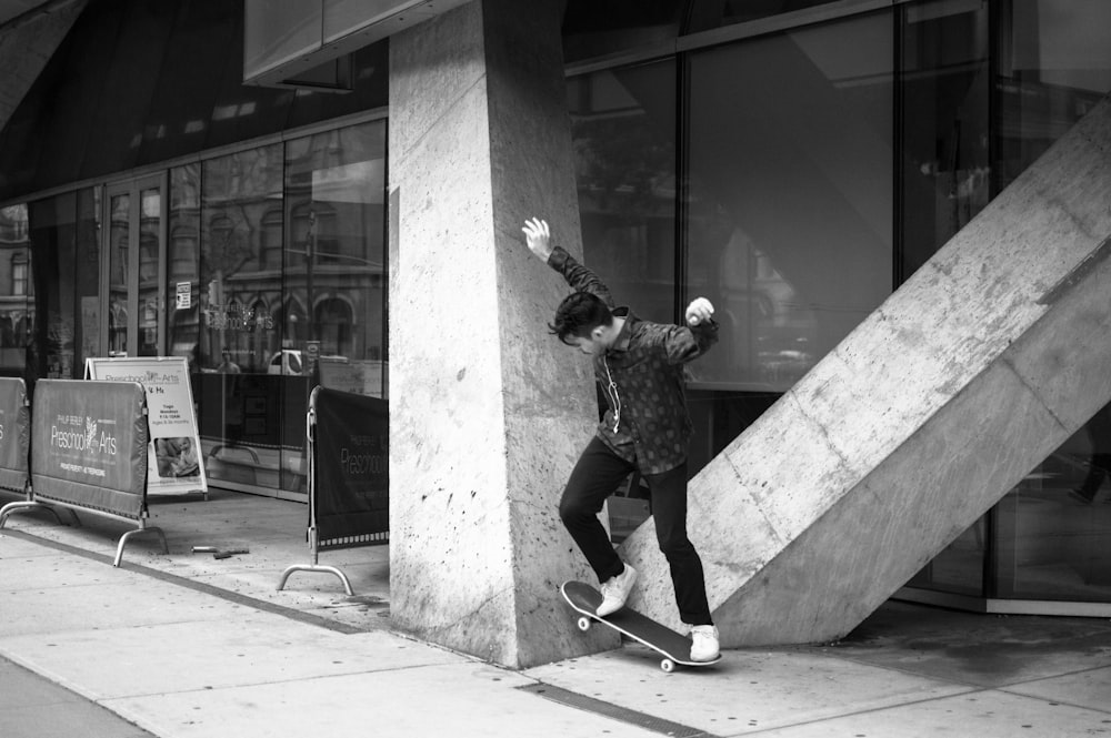 grayscale photo of man doing skateboard tricks