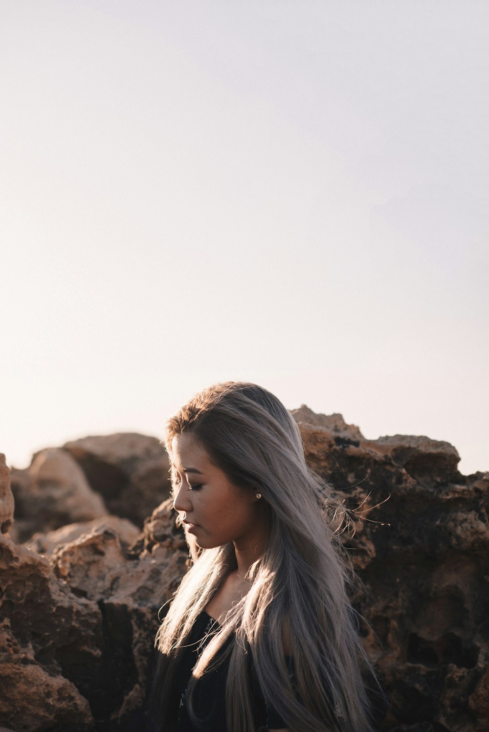 woman in white and black plaid shirt standing on brown rock formation during daytime