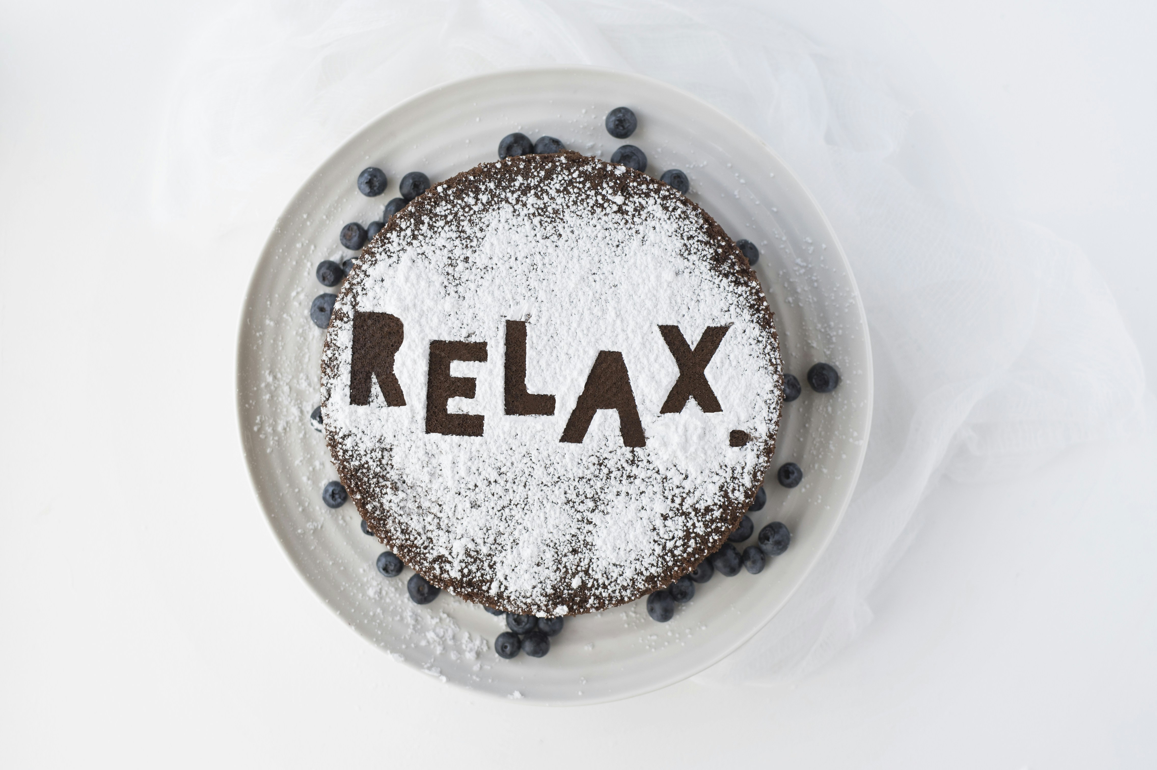 Chocolate and blueberry cake with powdered sugar that says Relax