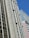 A cityscape featuring tall buildings with modern architectural designs against a clear blue sky. One of the buildings prominently displays a sign that reads 'CESAR BUSINESS'. The structures have a variety of rectangular windows, and one building has a beige and cream façade.