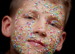 assorted-color sprinkler candies on boy's face