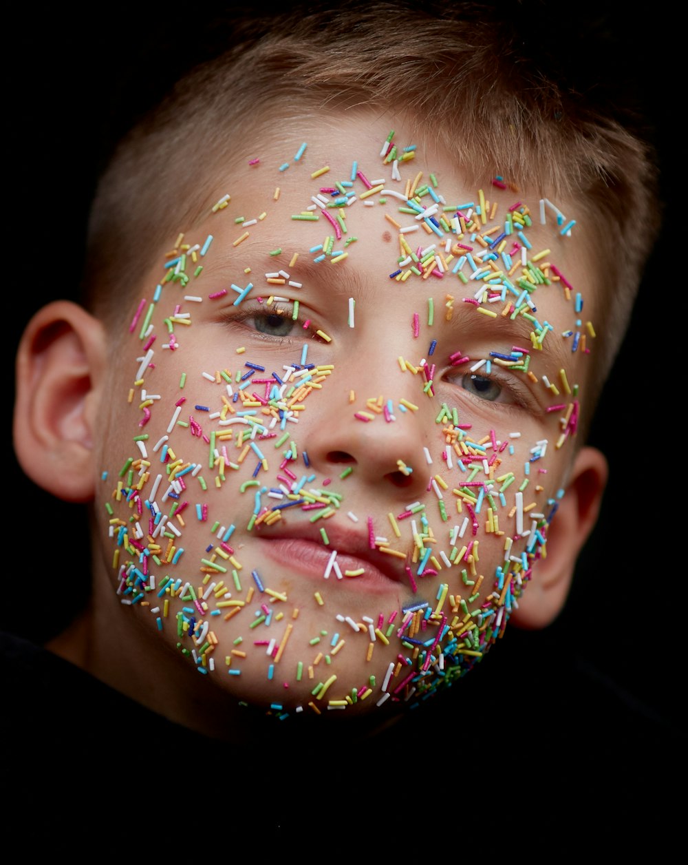 caramelle dell'irrigatore di colori assortiti sul viso del ragazzo