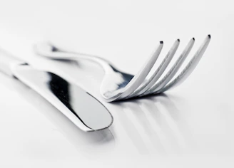 Close-up of a polished stainless steel cutlery set with a custom logo engraved on the handles.