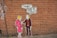 Street art on a brick wall depicting two stylized cartoon-like figures. One is a woman in a pink outfit, and the other is a man in a suit holding a speech bubble with the words 'Sydney, we need to talk!!'.