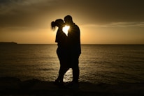 A couple enjoying a romantic sunset by the ocean, symbolizing honeymoon experiences.