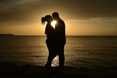 A couple enjoying a romantic sunset by the ocean, symbolizing honeymoon experiences.