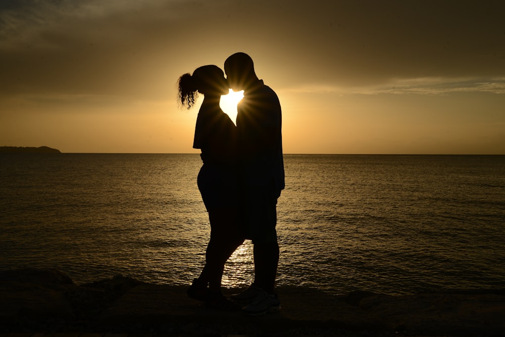 silhouette coppia baciare contro il sole