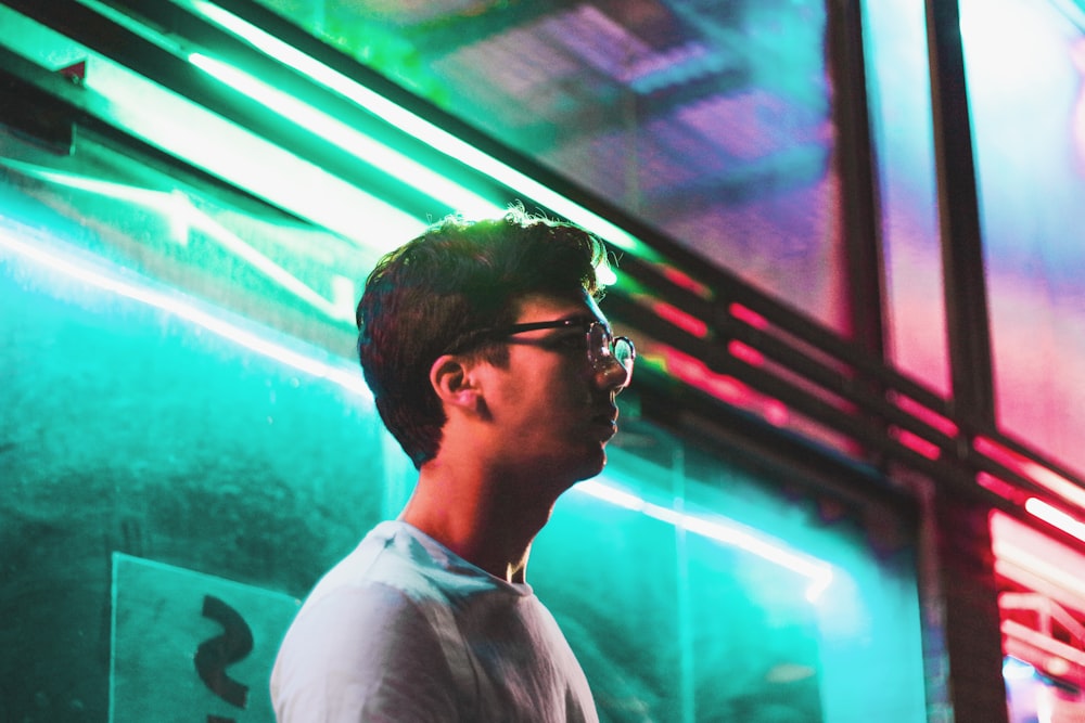 man wearing grey shirt beside green wall