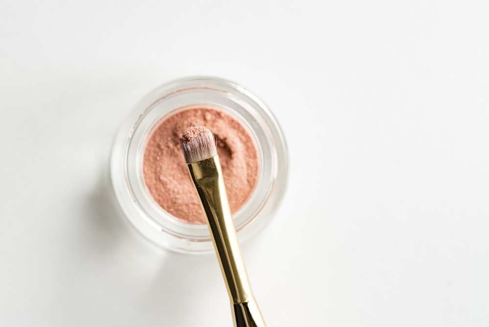 brauner Make-up-Pinsel vorne rosa Puder auf Glaskasten