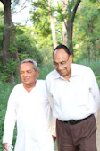 Elderly friends walking along a tree-lined path, chatting happily.