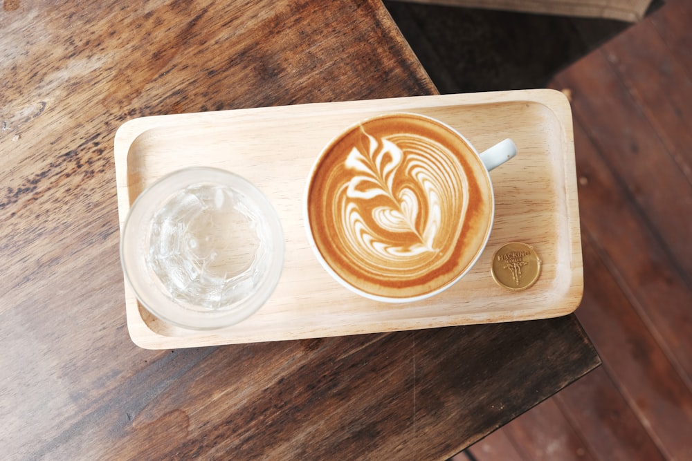 Taza de café de cerámica blanca en bandeja rectangular de madera marrón