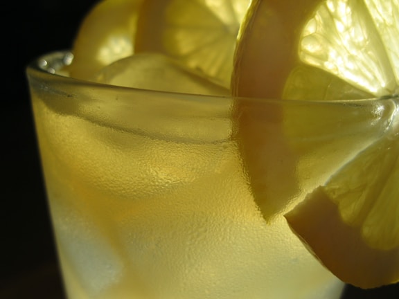 A chilled glass of turmeric and ginger infused lemonade glowing warmly in soft natural light.