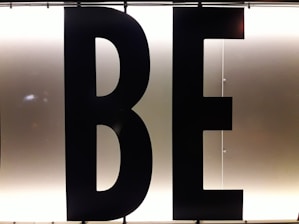 Black capital letters 'B' and 'E' against a bright, white illuminated background, possibly part of a sign or display board.