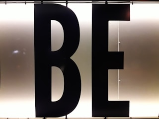 Black capital letters 'B' and 'E' against a bright, white illuminated background, possibly part of a sign or display board.