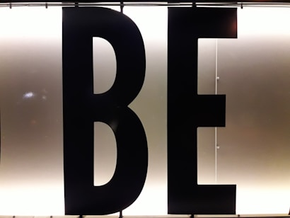 Black capital letters 'B' and 'E' against a bright, white illuminated background, possibly part of a sign or display board.