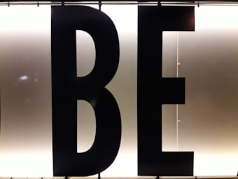 Black capital letters 'B' and 'E' against a bright, white illuminated background, possibly part of a sign or display board.