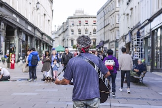 A lively street musician playing guitar with a small crowd enjoying the music.