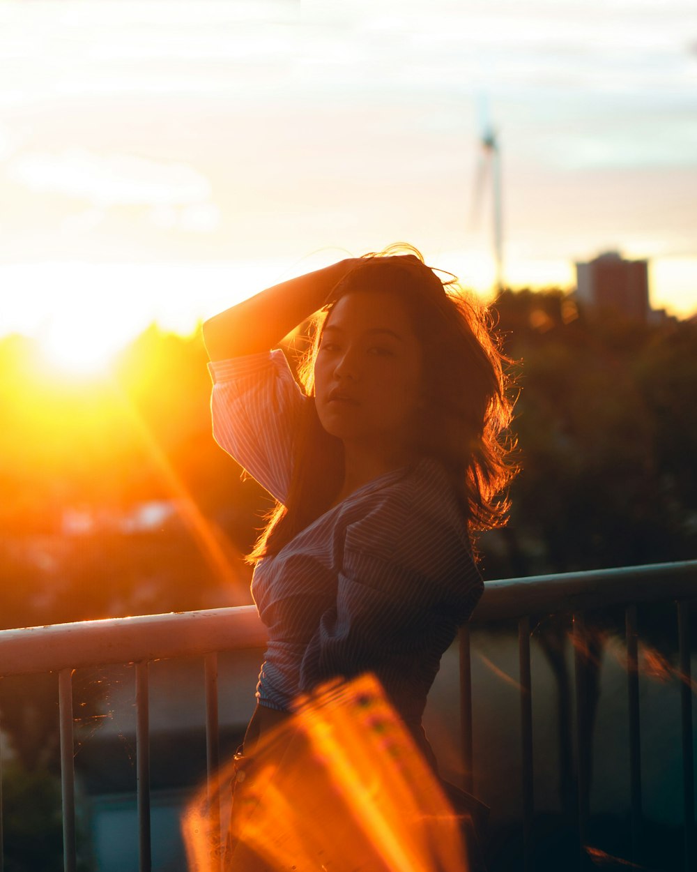 woman posing near handrail during sunset