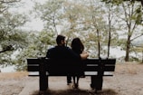 The couple sharing a quiet moment on a rustic wooden bench surrounded by autumn foliage.