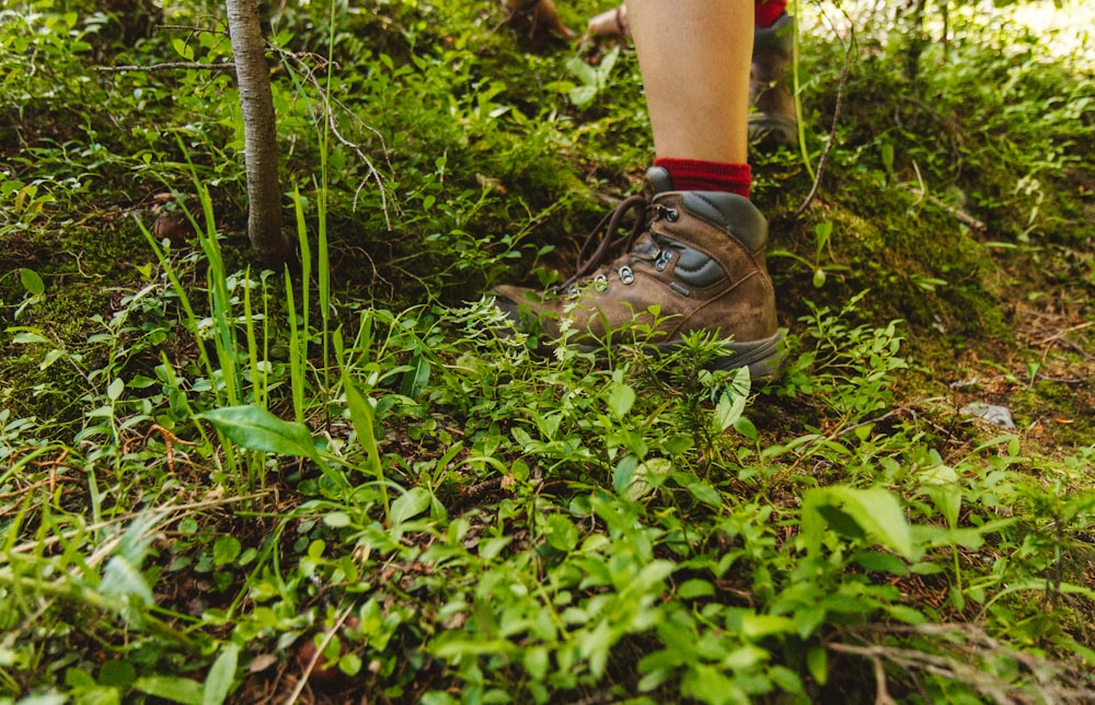 person wearing hiking shoes standing on green grass