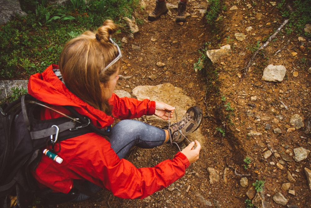 woman sitting on ground fixing her shoes