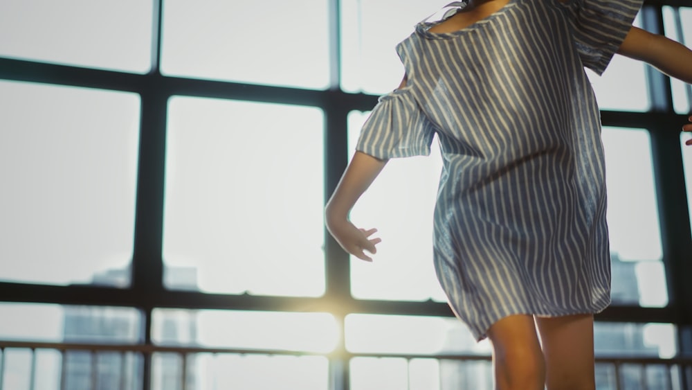 mulher usando mini vestido cinza perto da parede de vidro