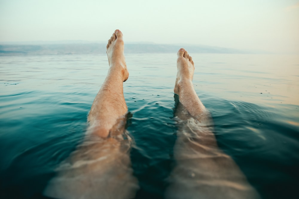 person's legs on water
