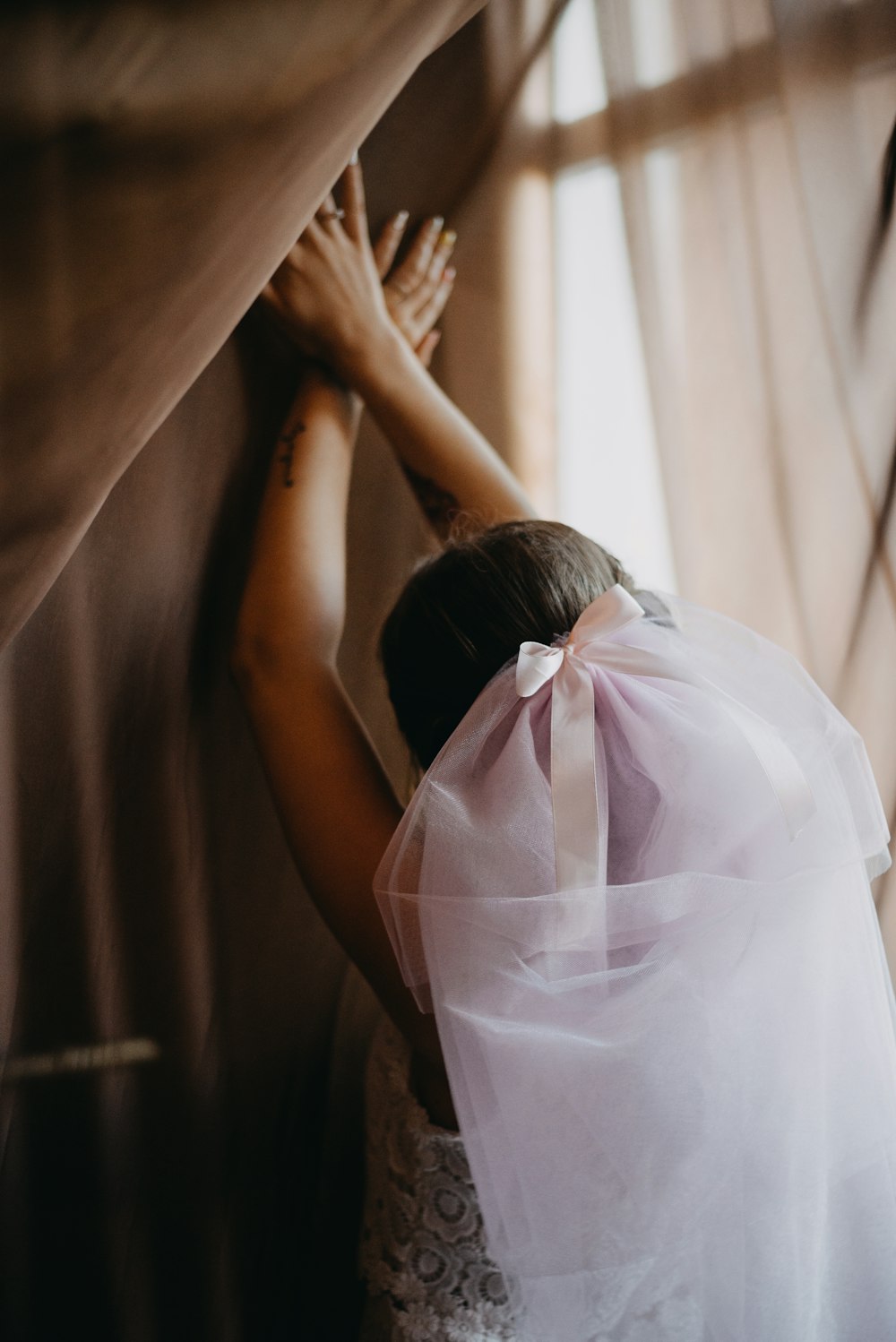 woman with veil with hands on wall