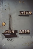A weathered metal door with several compartments, some with Chinese characters painted above them. The paint is worn, and there are visible rust and peeling layers. A keyhole is present, and the overall condition of the door suggests age and extensive use.