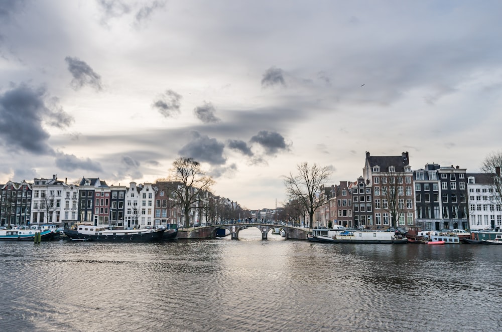 concrete buildings near body of water under cloudy sky