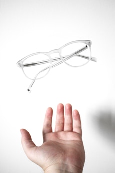 Close-up of a hand holding a clear contact lens with a bright, clean background.