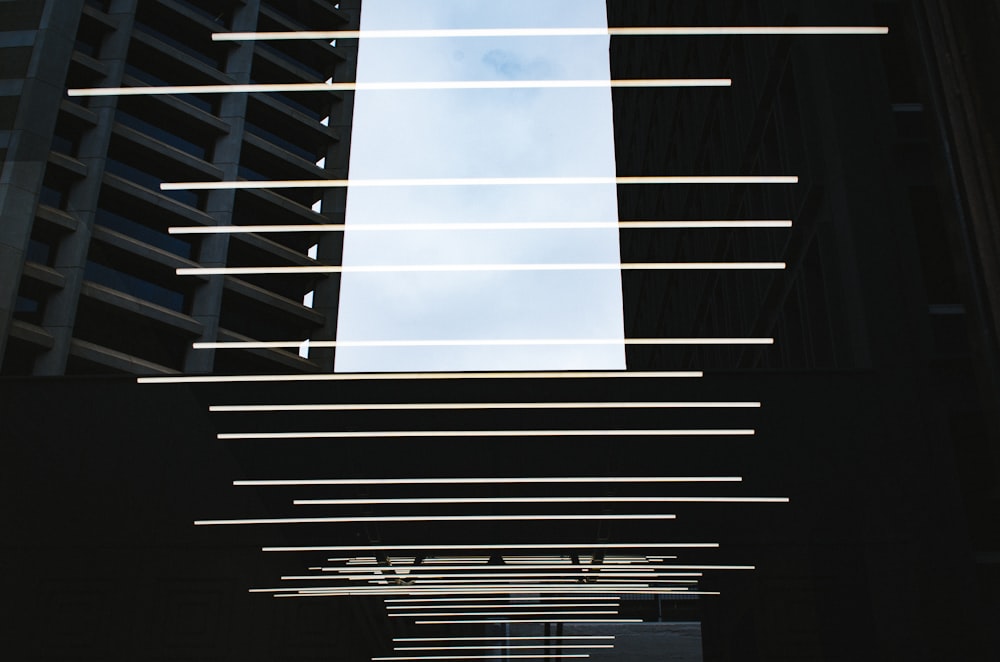 Rows of light beams above a walkway between buildings.