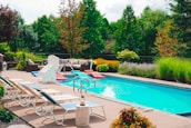 Happy family enjoying their backyard pool, smiling and relaxed on lounge chairs.