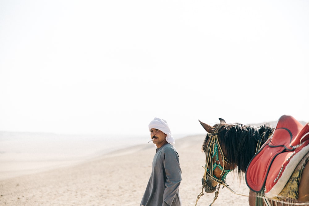 사막에서 말과 함께 걷는 남자