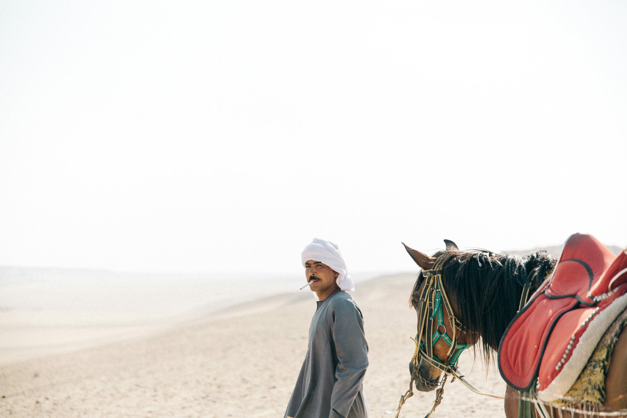 man walking with horse in desert