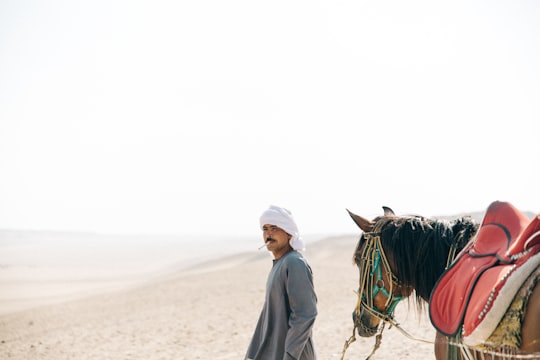 man walking with horse in desert in Saqqarah Egypt