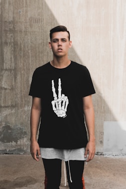 man wearing a black graphic tee standing near wall