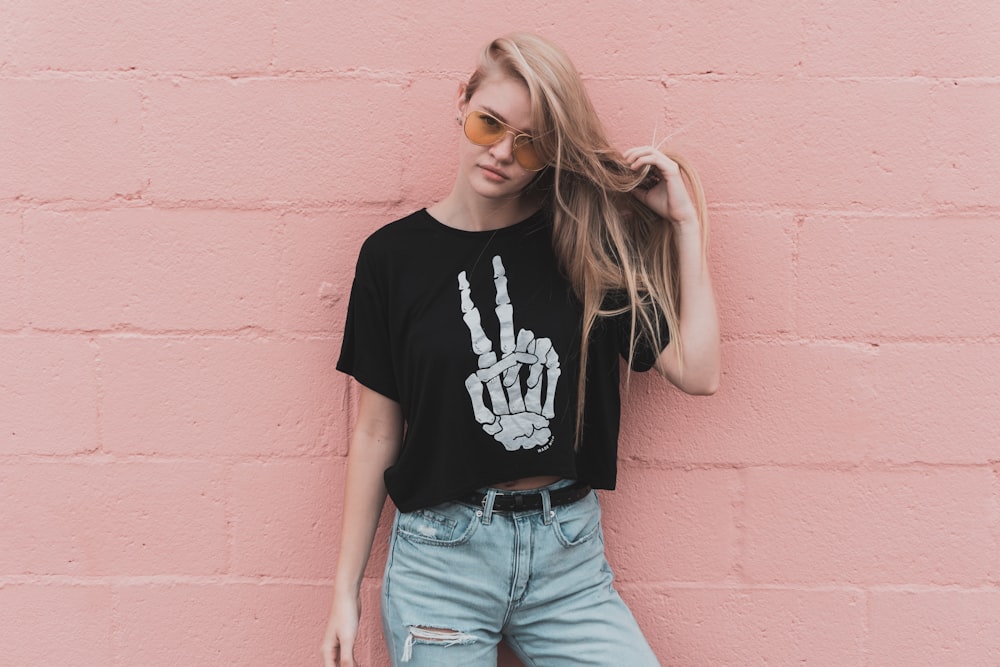 Trendy young woman in a skeleton shirt by a pink wall