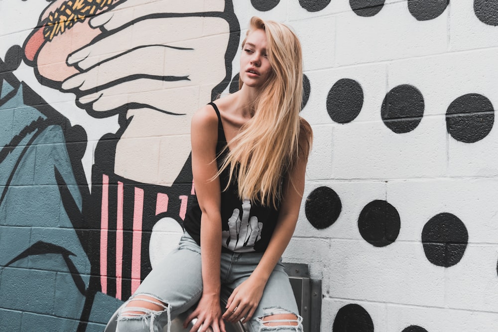 a woman sitting on a bench in front of a mural