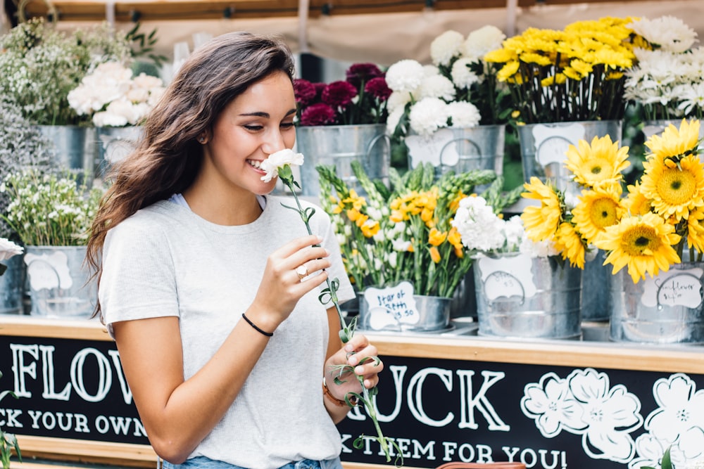 A woman at a floral stand in Nashville smiles while smelling a white flower