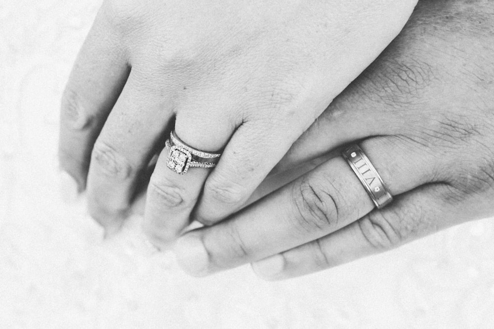 grayscale photo of woman's hand on top of man's hand